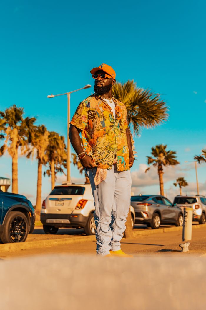 A fashionable adult enjoying a sunny day with palm trees and cars in the background.