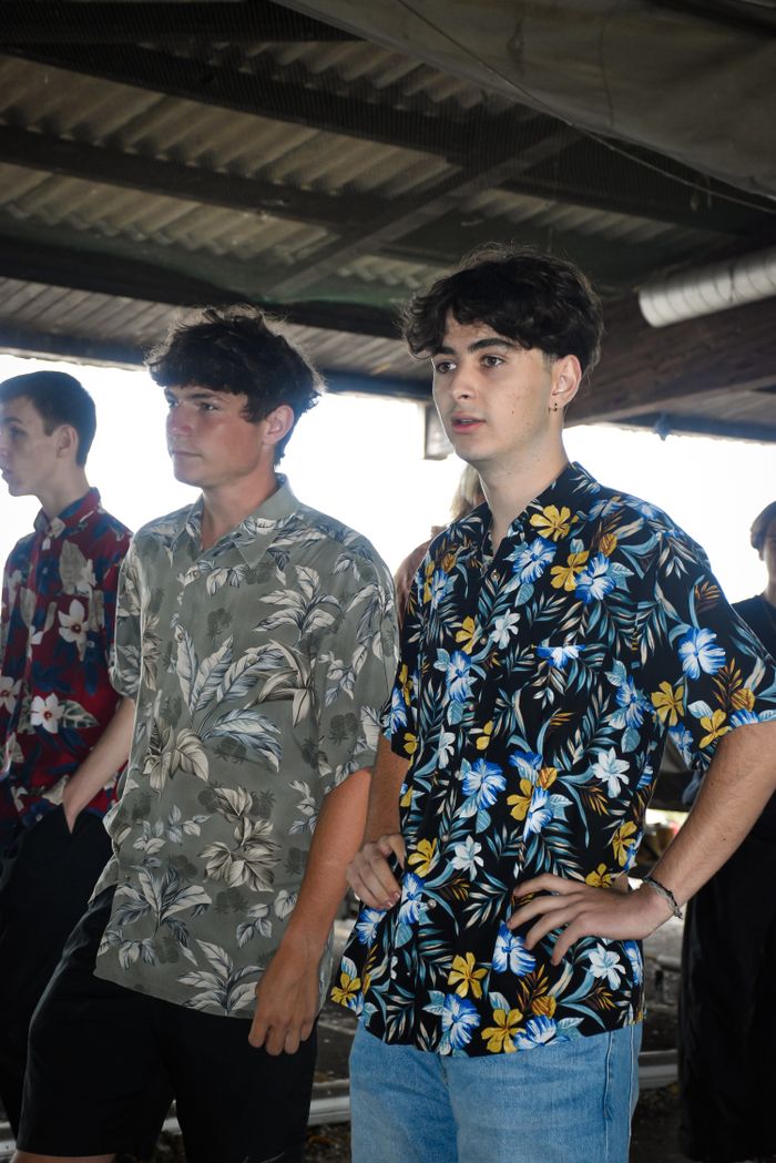 Young men wearing floral shirts in a casual indoor setting, showcasing youthful style and fashion.